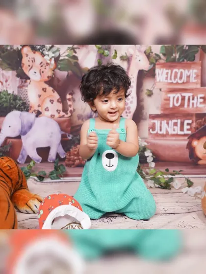 A close-up of a child enjoying the Jungle Safari setup. The decor includes a printed backdrop with jungle animals, wooden crates with "Welcome to the Jungle" signs, and plush animal toys.