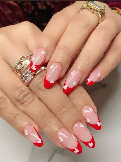This Valentine's-themed set features a vibrant red French tip on almond-shaped nails, with tiny hand-painted white hearts scattered across for a touch of romance.