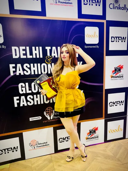 An influencer and award winner poses in front of our media wall, showcasing our key sponsors like Clinikally and Voods. We ensure our partners get prominent visibility with the creators and tastemakers who attend our events.