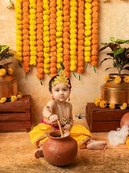 A sweet baby Krishna getting ready to enjoy some butter from his pot. The set is decorated with marigolds and brass pots for an authentic feel.
