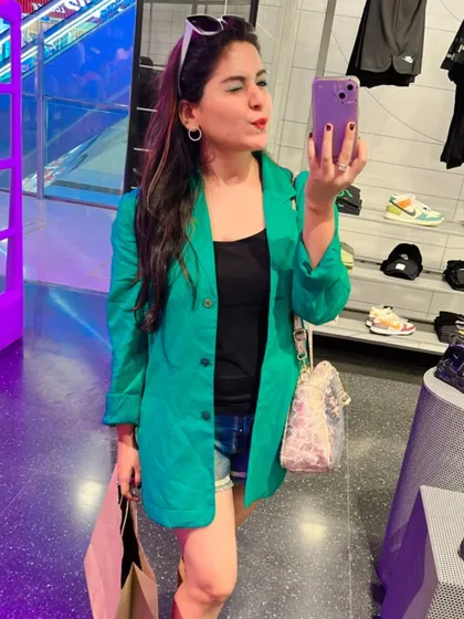 A shopping day selfie. I've styled a bright green blazer over a black top and denim shorts for a smart-casual look that's both comfortable and eye-catching.