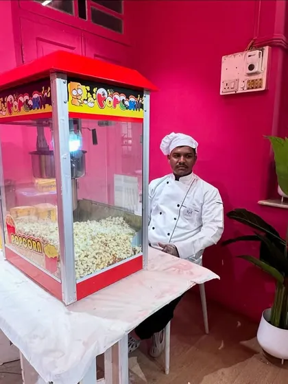 Our popcorn machine setup in a vibrant, pink-themed room, ready to serve guests at a house party. We can set up our compact stations anywhere.