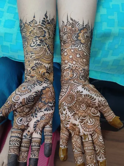 This design features a unique skyline or crown-like pattern at the top, adding a touch of modern flair to a traditional, full-coverage henna design.