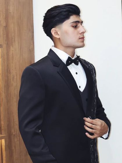 A side profile of a client in a custom black tuxedo. The fit is everything, ensuring the jacket sits perfectly on the shoulders and creates a sleek, elegant line.