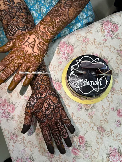 A fun shot celebrating the mehendi with a cake! This design features the initial 'H' and a name in Arabic.