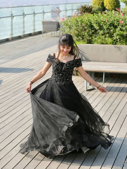 A playful twirl in a classic black ball gown. This dress is perfect for a fun and elegant look at a reception or formal party.