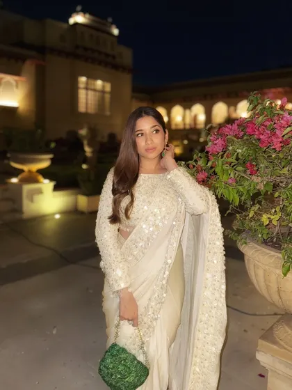 Another look at this stunning white saree. The right accessories, like these statement emerald earrings, can completely transform an outfit and tie the whole look together.