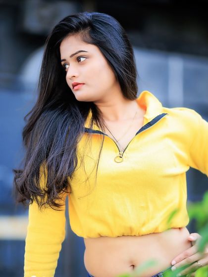 A beautiful three-quarter shot against a blurred background. The focus is entirely on her and the vibrant yellow of her top.