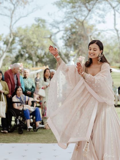 A bride twirling in her soft pastel lehenga during her Mehendi ceremony. The look is light, happy, and perfect for a daytime event.