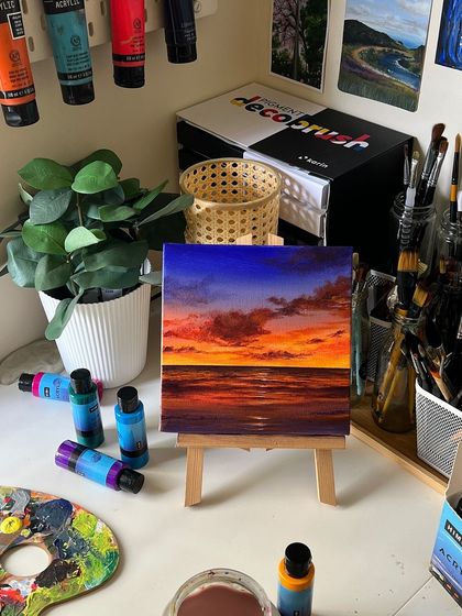 A styled shot of the vibrant sunset painting on an easel, with my art supplies arranged neatly around it.