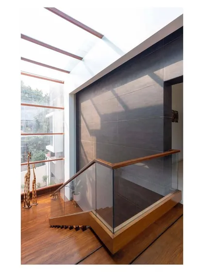 A view from the top of the staircase in the "House with Parallel Planes," looking down into the atrium. The glass railing maintains a sense of openness and transparency.