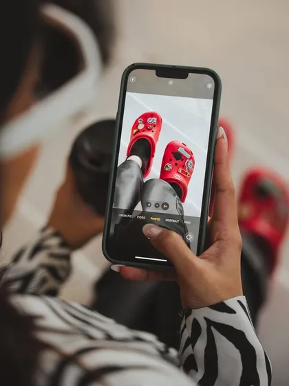 A 'photo-within-a-photo' shot for a Crocs social media campaign. This meta-narrative is modern and engaging, showing how the product is not just worn but also shared and celebrated online.