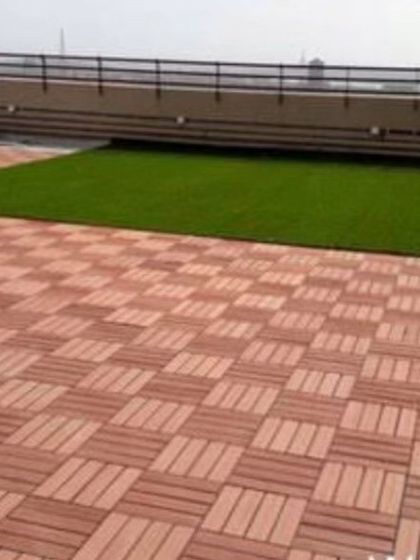 A rooftop installation showing a combination of WPC deck tiles in a basketweave pattern next to a patch of artificial grass. This is a practical solution for defining different areas on a terrace.