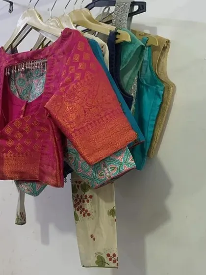 A collection of custom-stitched blouses hanging in my workshop. I can create any style you need, from traditional brocade blouses to modern sleeveless designs.