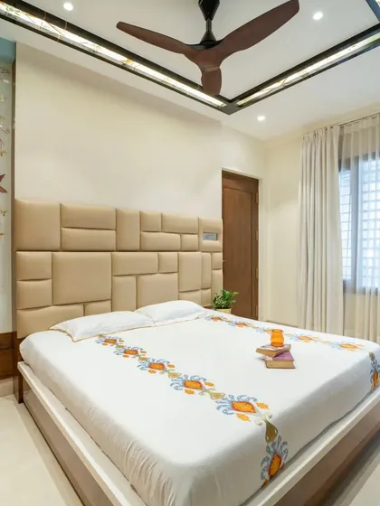 A calm and elegant bedroom design featuring a custom upholstered headboard and a beautiful etched glass partition.