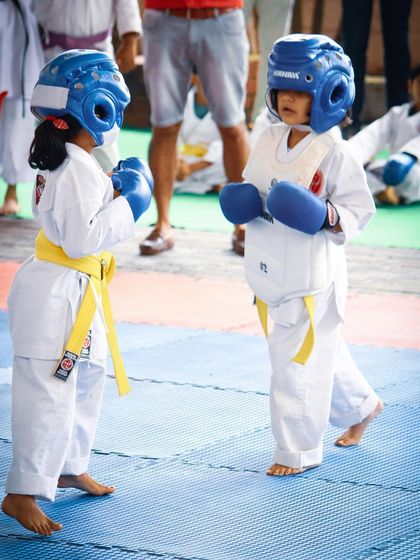 Two young karatekas face off, ready to begin their sparring match. This image captures the focus and readiness we instill in our students from their very first competition.