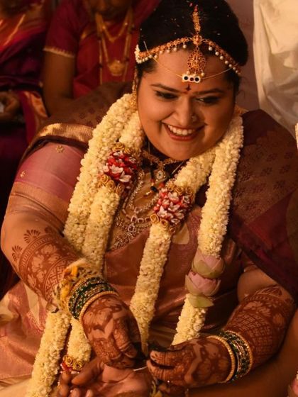 A candid moment from a wedding, showing the bride's joyful smile and her beautifully adorned hands and feet.