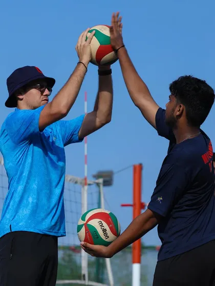 A coach provides hands-on guidance to a player, correcting their setting form. This one-on-one attention to detail is a core part of our training program.