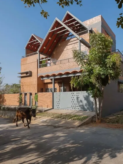 This is the Madhura residence, designed as two homes stacked together. I used compressed stabilized earth blocks (CSEB) and prominent sloping tile roofs to connect the design to the family's ancestral roots while creating a modern, functional urban home with a generous front garden.