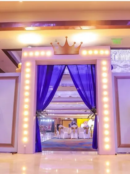The majestic entrance to a prince's birthday party. The crown-topped archway with warm lights and royal blue drapes sets a regal tone from the moment guests arrive.