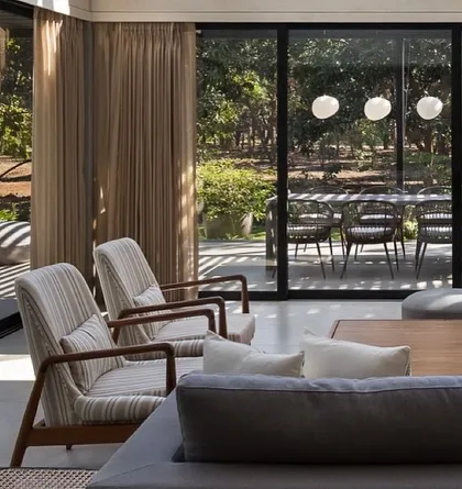The living room's glass walls slide open to seamlessly connect with the outdoor dining terrace. This design choice erases the line between indoors and out, allowing for a fluid living experience that embraces the natural surroundings.