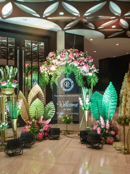 A closer look at the entrance decor, featuring large, illuminated leaf installations and ornate golden cages, blending artistic elements with traditional floral design.