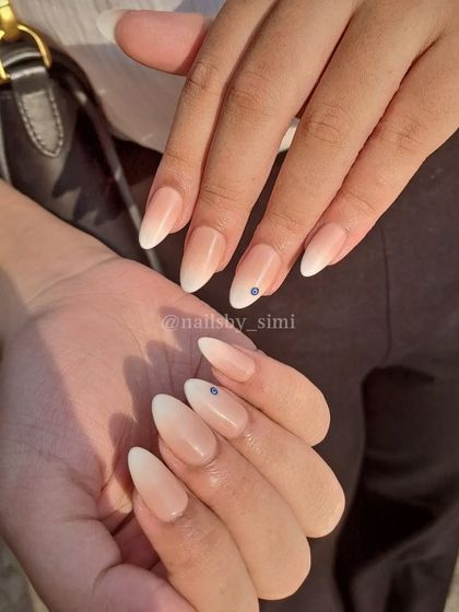 Classic baby boomer ombré nails with a tiny blue rhinestone for a subtle touch of evil eye protection.