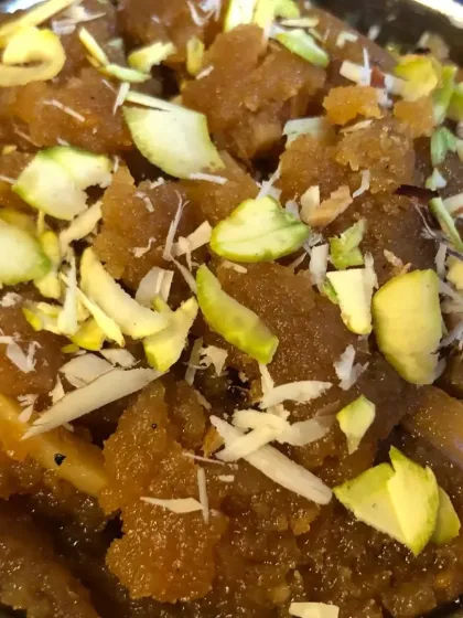 A bowl of rich Moong Dal Halwa, slow-cooked in desi ghee and garnished with slivered almonds and pistachios. This is a classic winter dessert that warms the heart.
