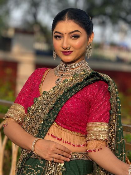 This model showcases a modern party look with a sleek, low bun. This hairstyle is perfect for highlighting statement earrings and a decorative blouse.