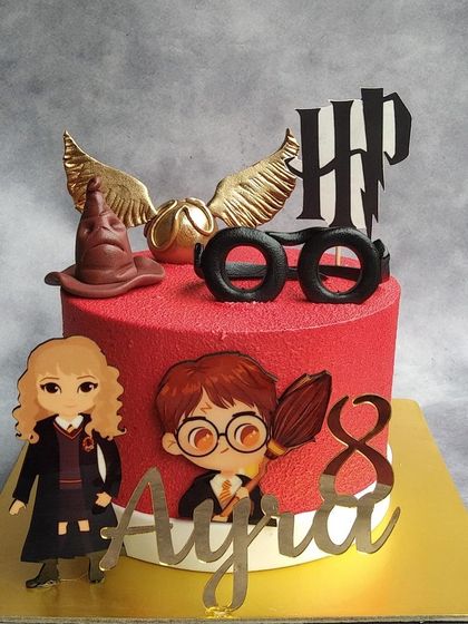 A magical Harry Potter cake for an 8th birthday. We decorated this red velvet cake with iconic symbols like the golden snitch, sorting hat, and Harry's glasses, all crafted from edible materials.