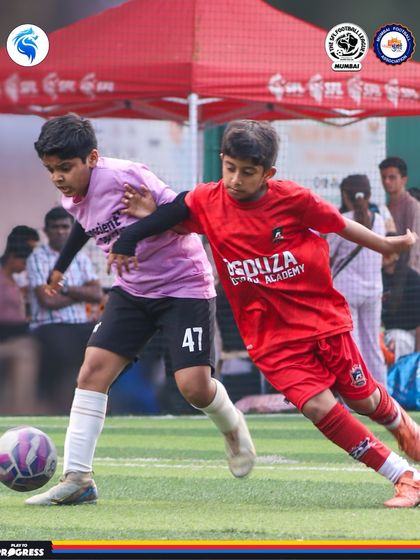 A tough battle in the midfield. The red and pink jerseys create a vibrant visual of the competition on the pitch.