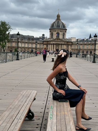 A thoughtful moment on the Pont des Arts bridge in Paris. The bow in my hair adds a whimsical touch to this otherwise classic and sophisticated look.