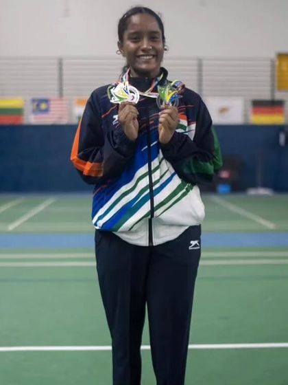 **A Display of World-Class Achievement.** Aaditya Yadav stands proudly with her collection of medals from the World Deaf Championship, a monumental achievement for her and the academy.