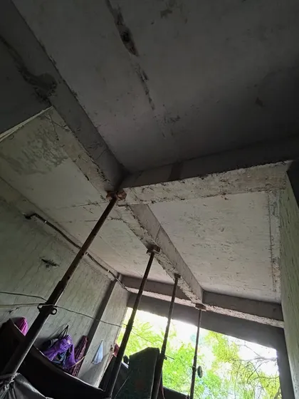 An interior view during construction, showing the exposed concrete beams and ceiling before plastering. Temporary supports are in place while the concrete cures to its full strength.