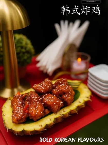 Bold Korean flavors plated with creativity. This dish features crispy chicken coated in a sweet and spicy gochujang sauce, served in a hollowed-out pineapple for a presentation that is both rustic and chic.