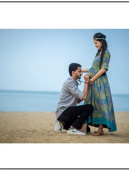 A playful moment on the beach as the dad-to-be listens to the baby with a stethoscope.