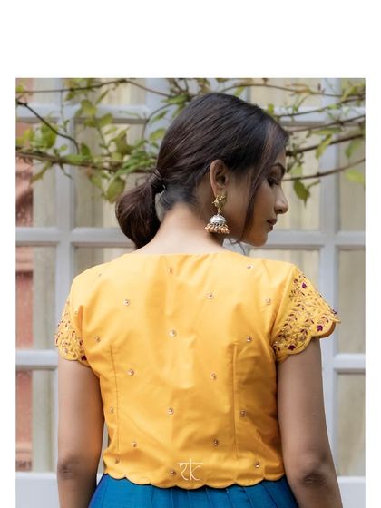 The back of the yellow jacket shows the delicate embroidery and scalloped hem, a testament to the detailed craftsmanship.