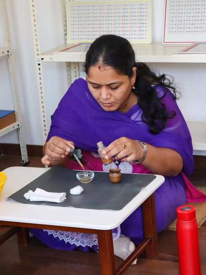 An adult learner practices with a dropper and bowl, a classic Practical Life activity. This focused work is not just for children; it helps our educators understand the precision, concentration, and fine motor control that these simple materials develop.