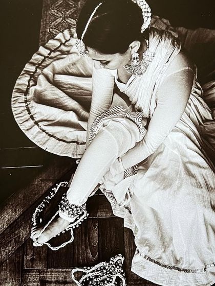 An overhead shot of me fastening my ghungroos (ankle bells), a classic ritual for a Kathak dancer, captured in a timeless black and white style.