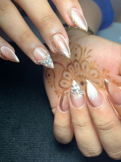 A close-up of stiletto extensions with a cat-eye base and diamond-like crystal tips. This is a perfect look for an engagement or cocktail party.