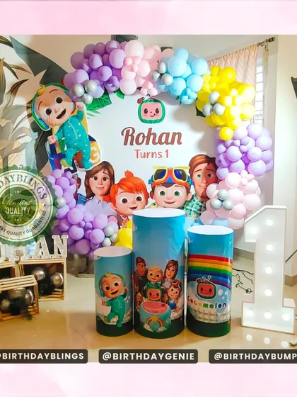 This Cocomelon first birthday party features a colorful balloon arch and themed plinths. The light-up number '1' and character cutouts make it a fun and festive scene.