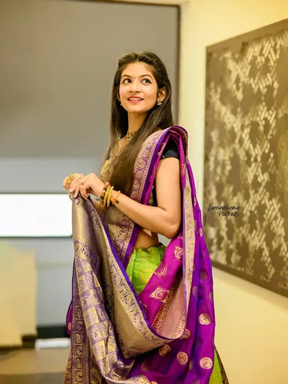 A three-quarter portrait capturing a sweet, candid moment, with the model holding her saree's pallu.