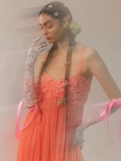 An ethereal shot using slow shutter speed to create a dreamlike, painterly effect. The styling, with delicate lace gloves, floral hair details, and flowing ribbons, was designed to evoke a sense of fragile beauty and poetic movement.