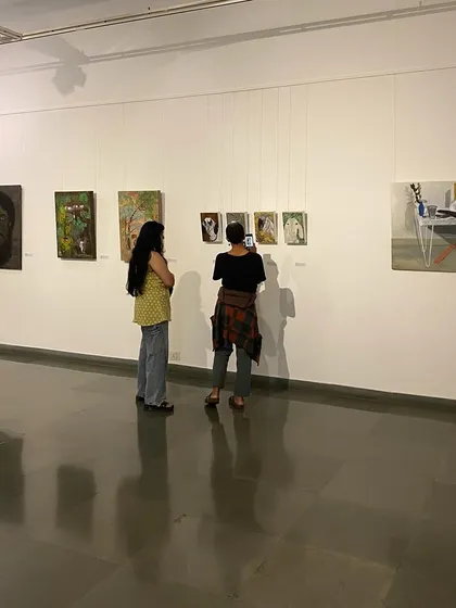 Two visitors photographing the artworks of Unnikrishnan C.