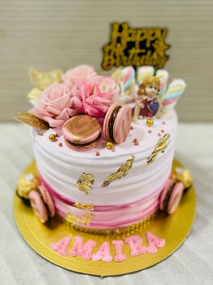 The finer things in life: a beautiful pink cake with gold leaf, macarons, and delicate pink roses.