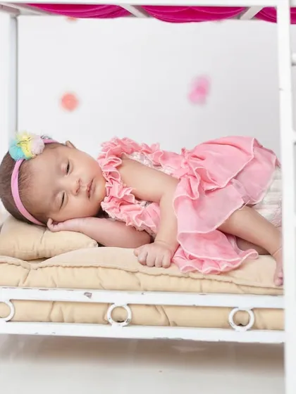 A close-up of one of the twins sleeping peacefully on the bottom bunk of the miniature bed prop.