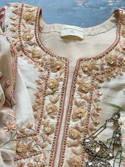 A close-up of the neckline, showing the intricate Doriwork and floral patterns.