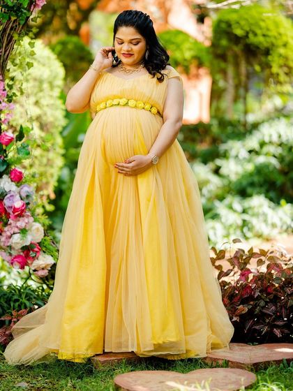 A full-length solo portrait showcasing a beautiful, bright yellow maternity gown. The color radiates joy and warmth, perfect for a sunny garden photoshoot.