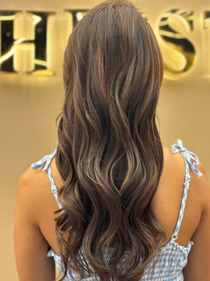 A back view of beautifully blended highlights on long hair. The soft waves enhance the multi-dimensional color, creating a look that is both glamorous and natural.