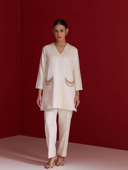 An ivory white kurta set with minimalist elegance. The highlight is the delicately embroidered pockets, adding a touch of unique charm.